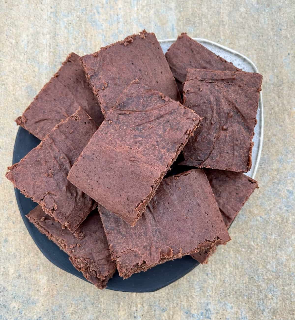 Halo Top chocolate fudge brownies stacked on ceramic serving plate.