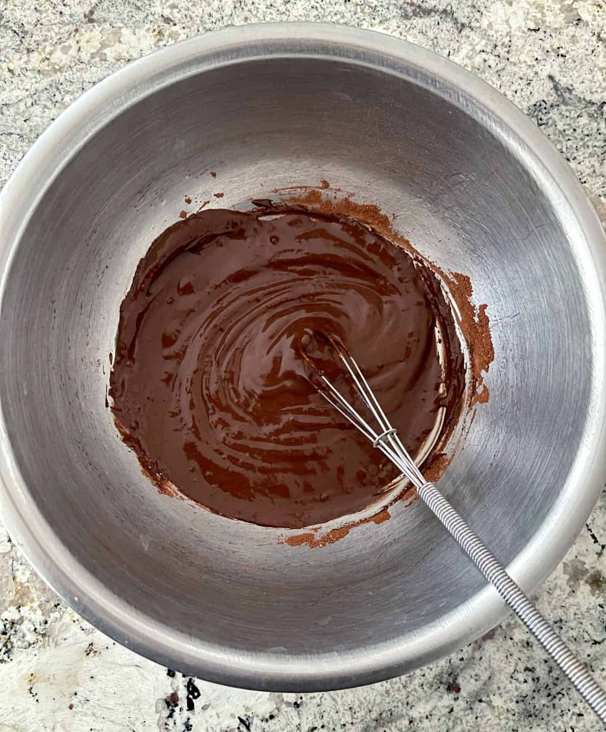 Mixing flourless chocolate mug cake batter in mixing bowl with whisk.