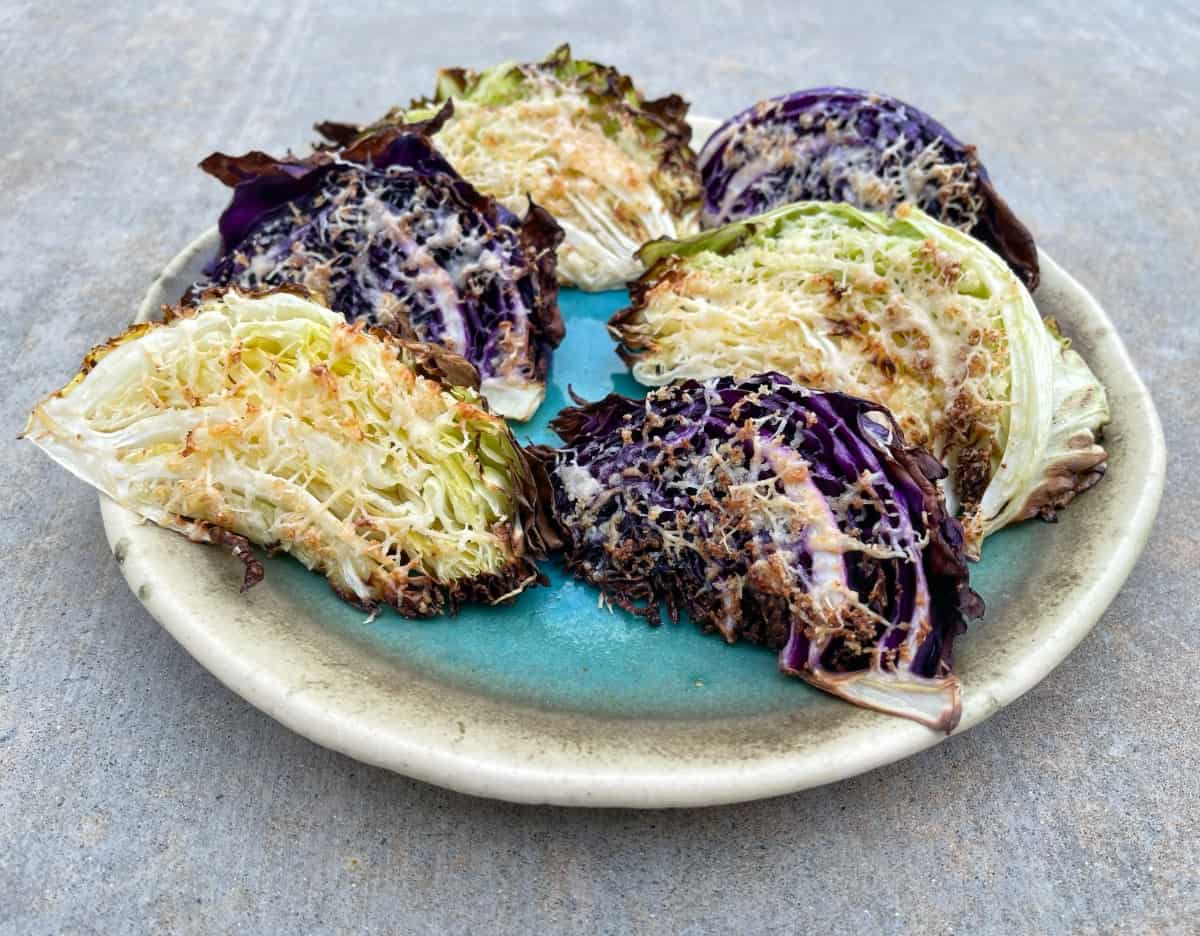 Six wedges Parmesan Roasted Cabbage Wedges on pottery serving plate.