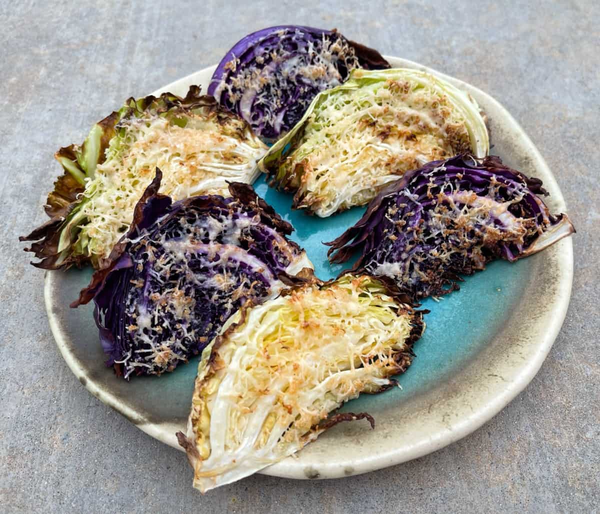 Six air fried Parmesan crusted cabbage wedges on ceramic serving platter.