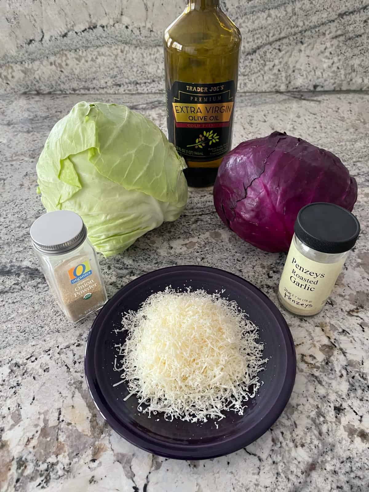 Ingredients including head of green cabbage, head of purple cabbage, grated Parmesan cheese, onion powder and garlic powder.