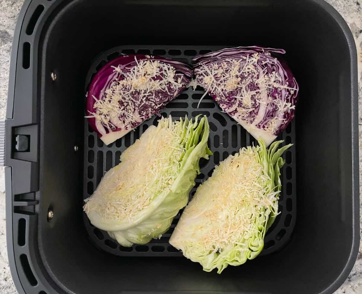 Uncooked parmesan garlic cabbage wedges in air fryer basket.