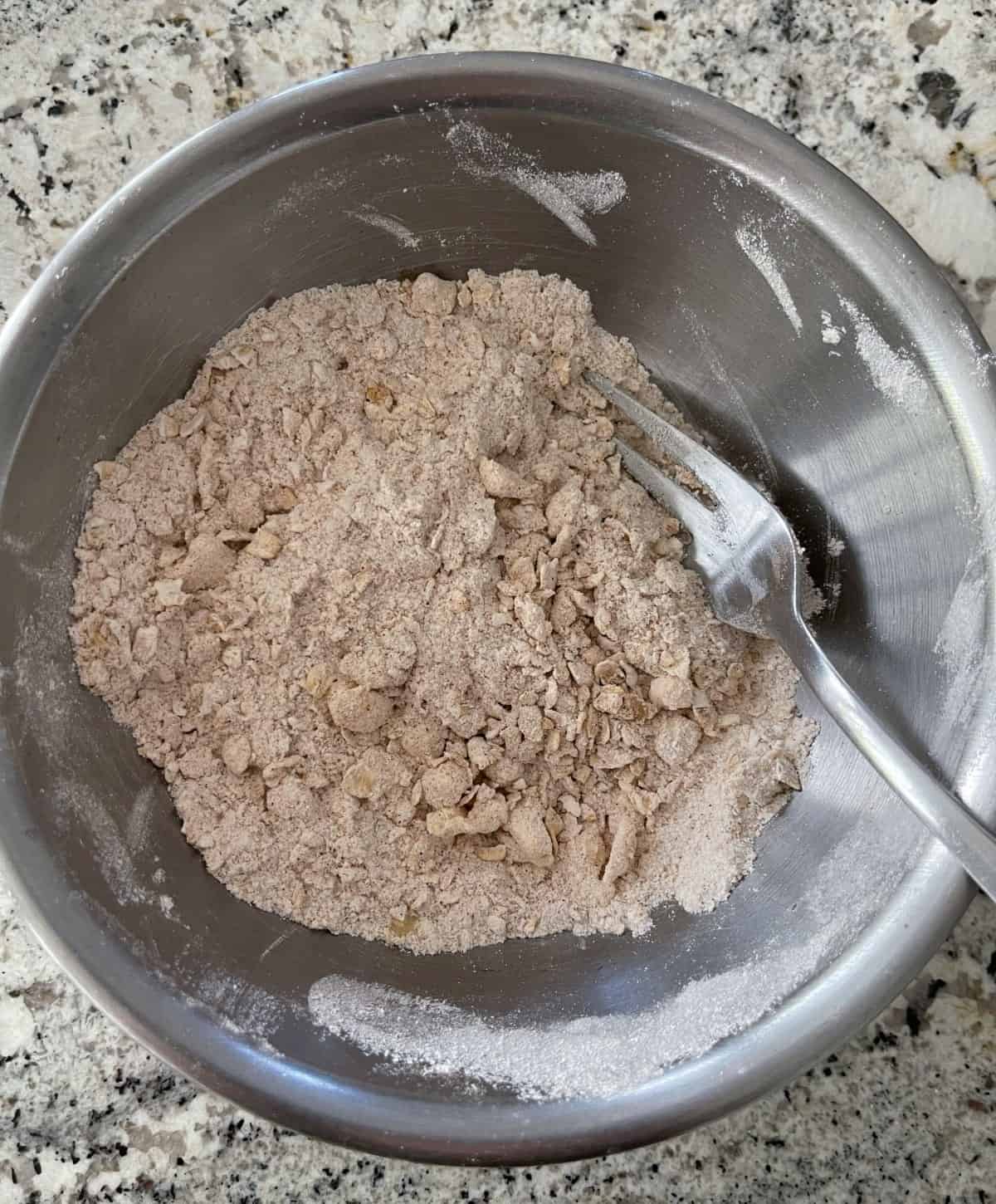 Mixing Truvia sweetener, flour, quick oats, cinnamon and cold butter in a mixing bowl to create a crumble topping.