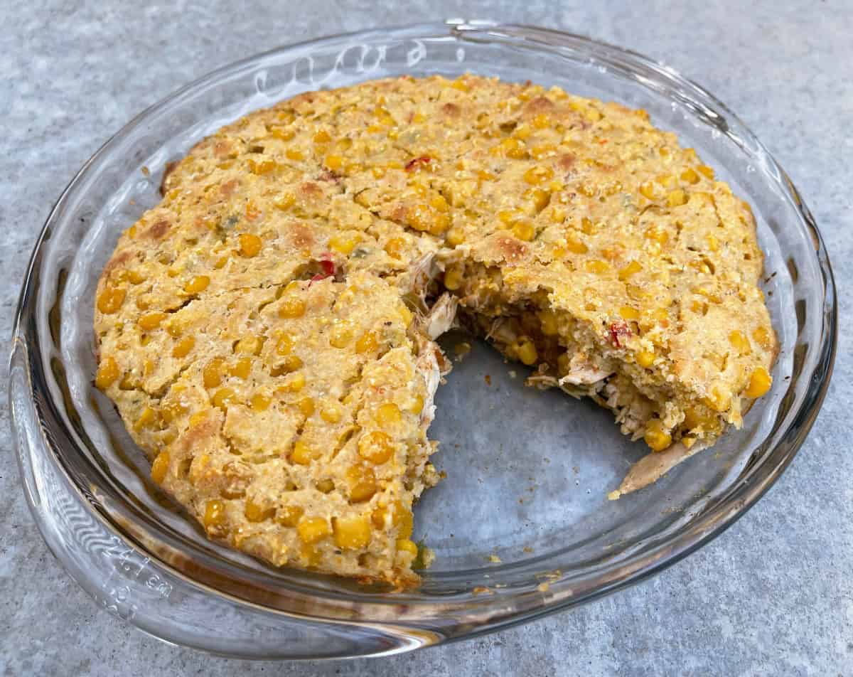 Chicken tamale pie in glass pie dish with wedge cut out.