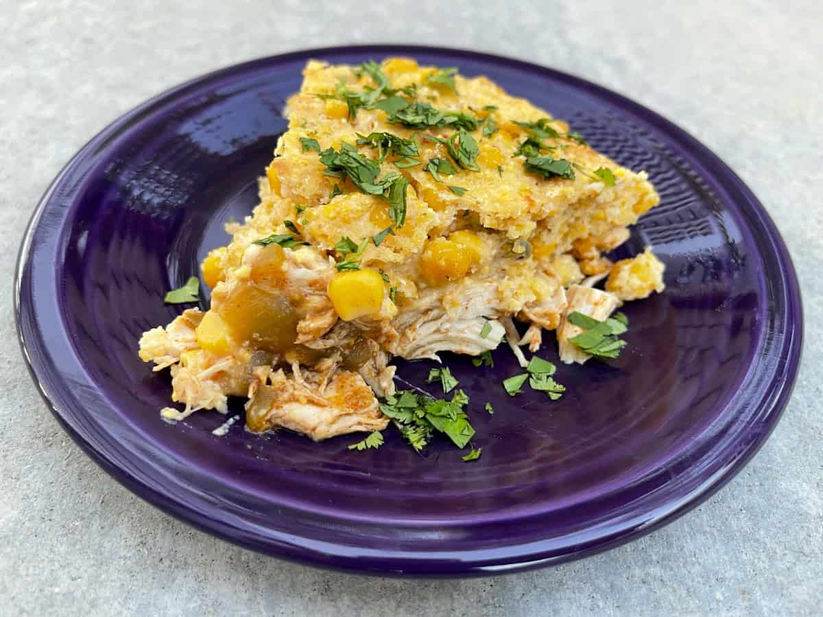 Wedge of chicken tamale pie garnished with chopped cilantro on small purple plate.