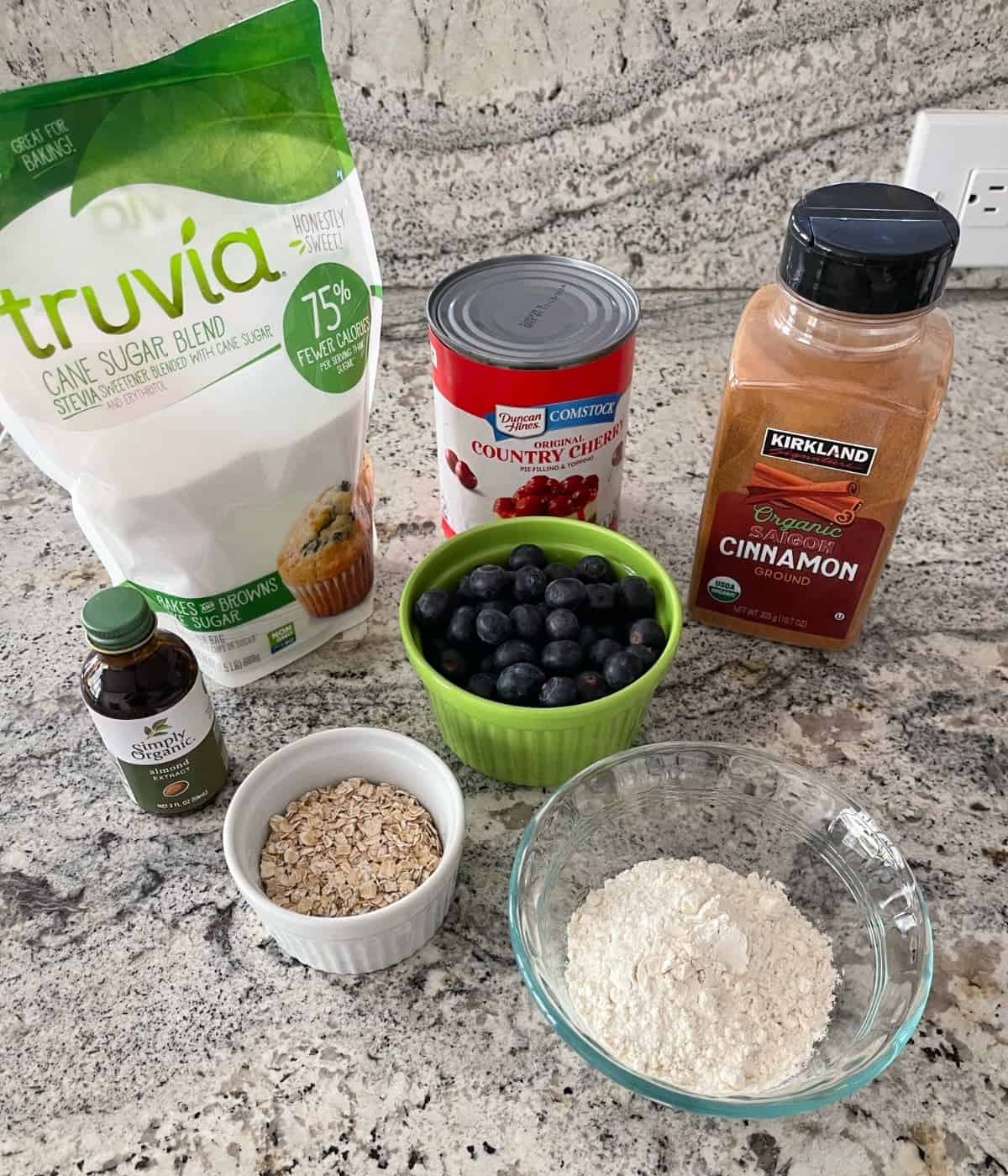 Ingredients including Truvia Baking Blend, can of cherry pie filling, cinnamon, almond extract, fresh blueberries, quick oats and all-purpose flour.
