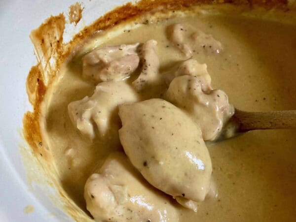 Cooked Chicken Thighs with Cream of Chicken Soup White Ceramic Slow Cooker Insert Wooden Spon