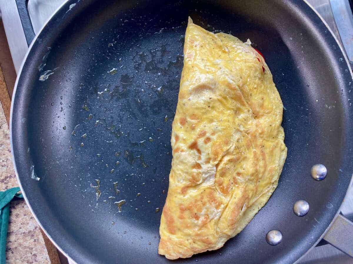 Crepe style omelette folded in nonstick skillet ready to transfer to plate.