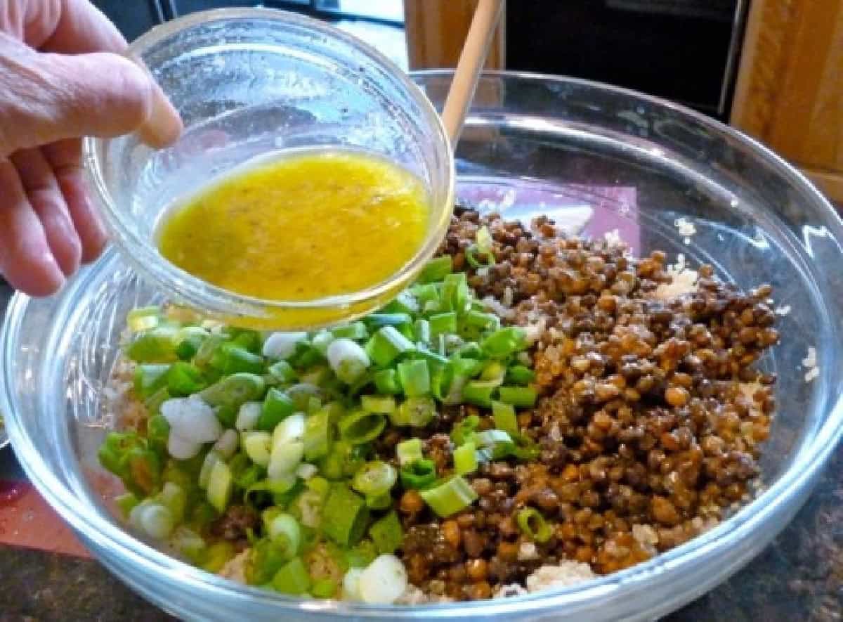 Adding Lemon Dressing to Large Glass Mixing Bowl of Quinoa, Lentils and Scallions