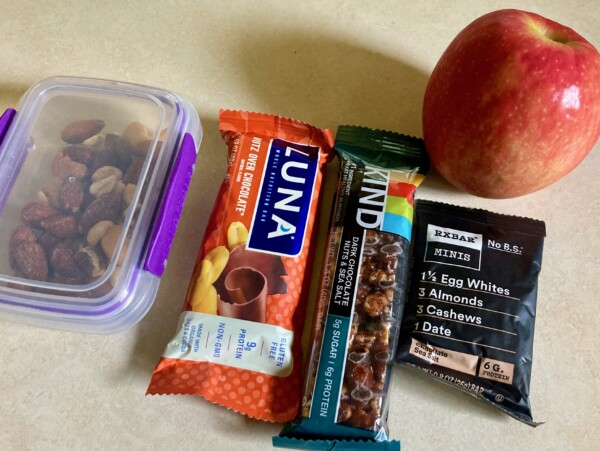 Snacks on counter: apple, protein bars, small container nuts