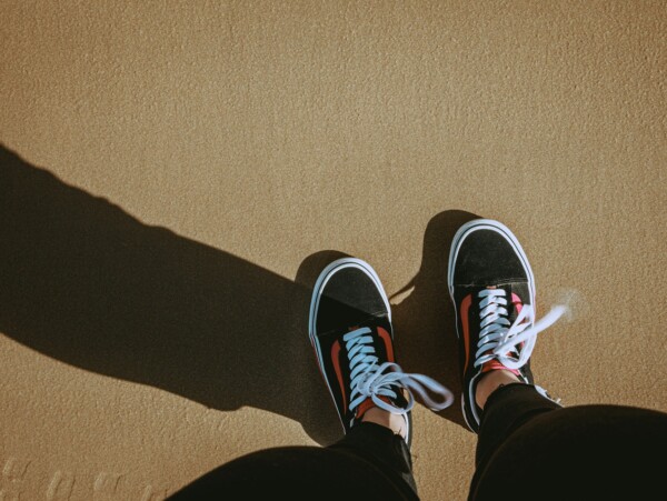 looking down at feet with black and orange sneakers on them