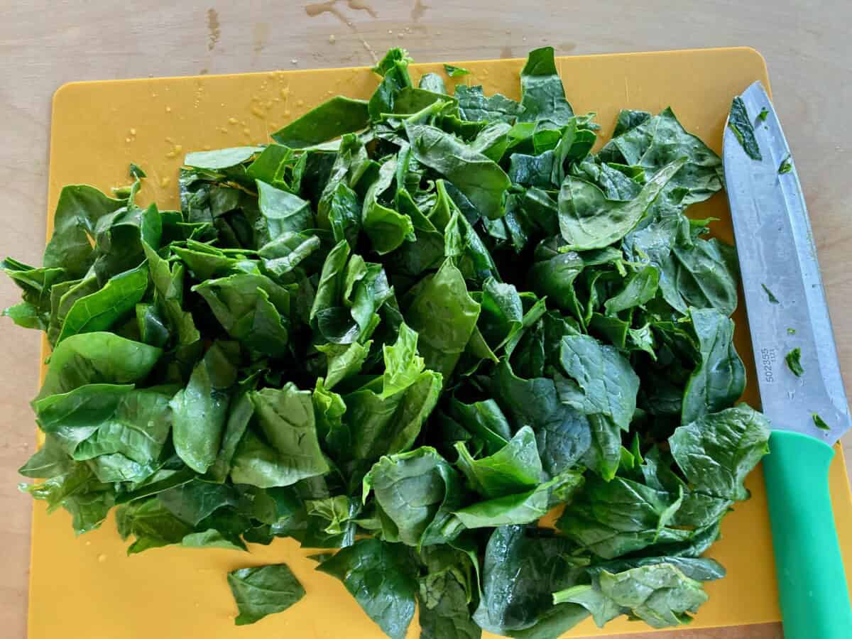 Chopped spinach on yellow cutting board.