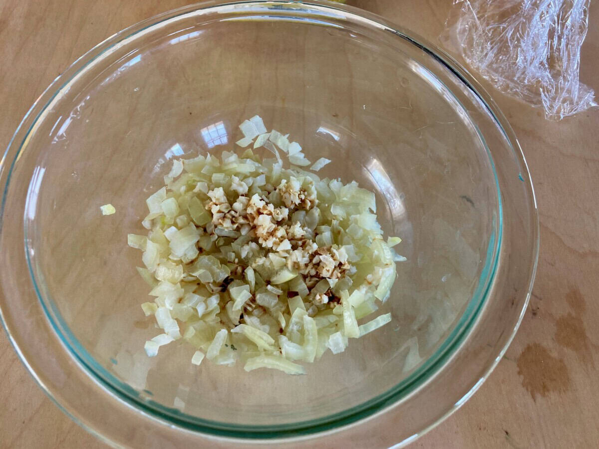 Onion, garlic and seasonings in clear pyrex bowl.