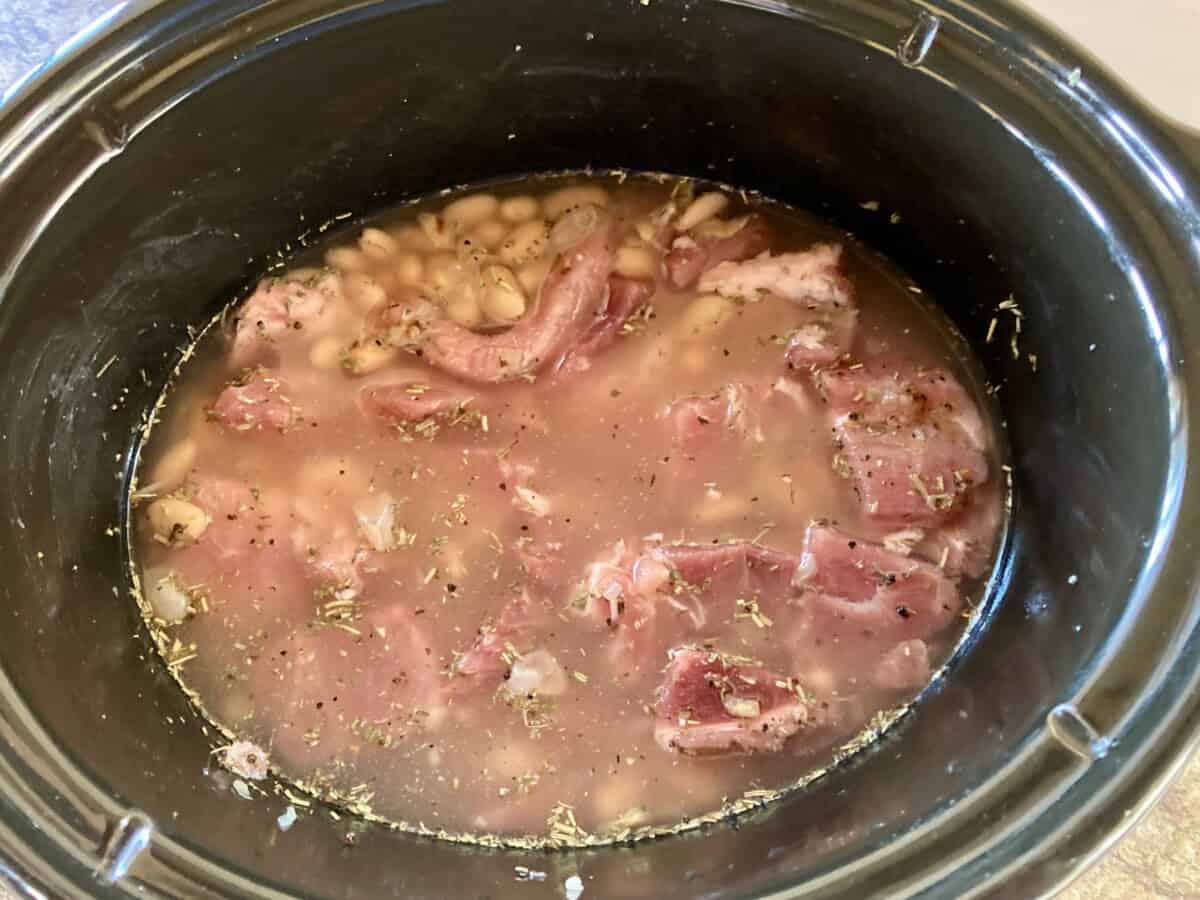 Pork, white beans, seasonings, broth in crock pot read to cook.