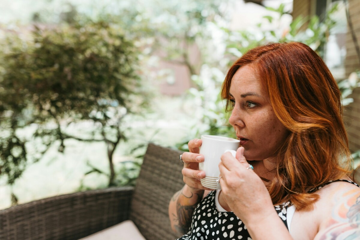 red headed woman sitting drinking a mug of coffee