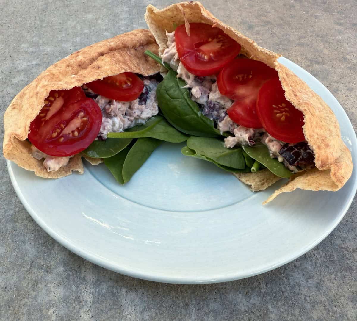 Greek Tuna Salad stuffed pita pocket on small blue plate.