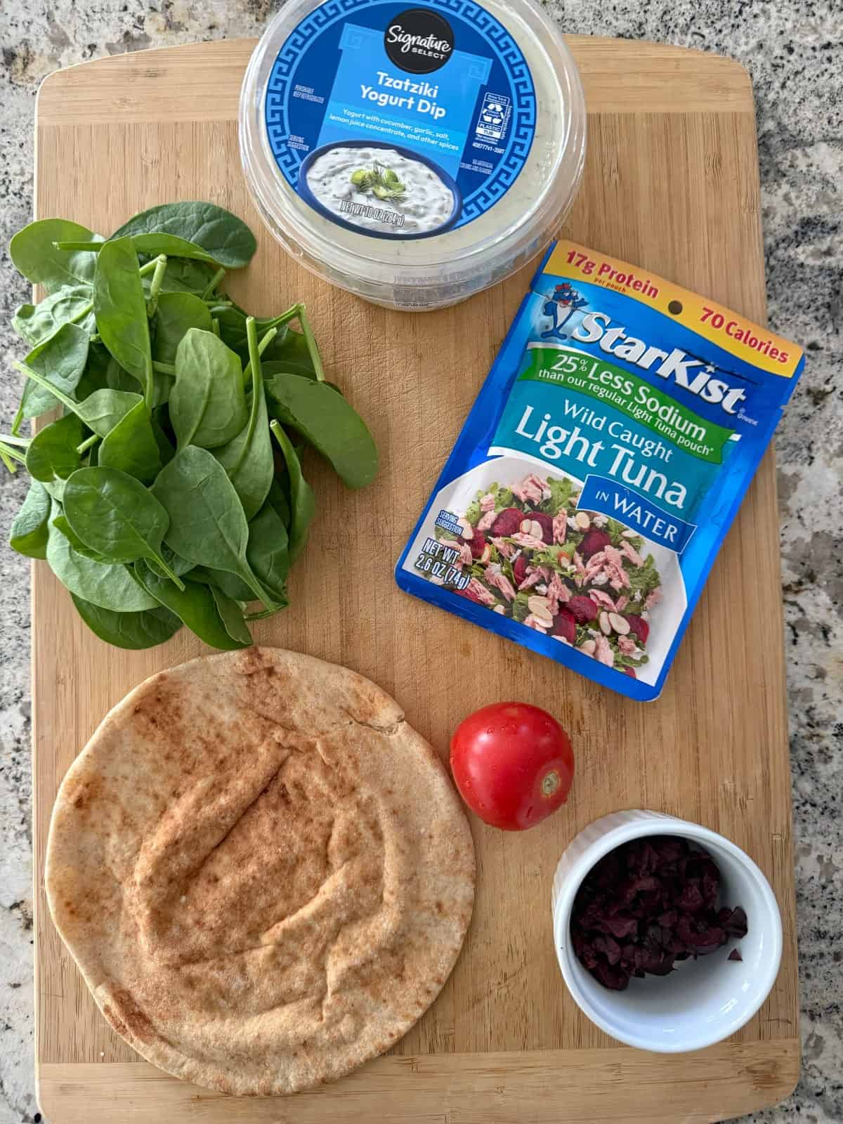Ingredients including tzatziki yogurt dip, fresh baby spinach, low sodium tuna packet, Campari tomato, whole grain pita and chopped Kalamata olives.