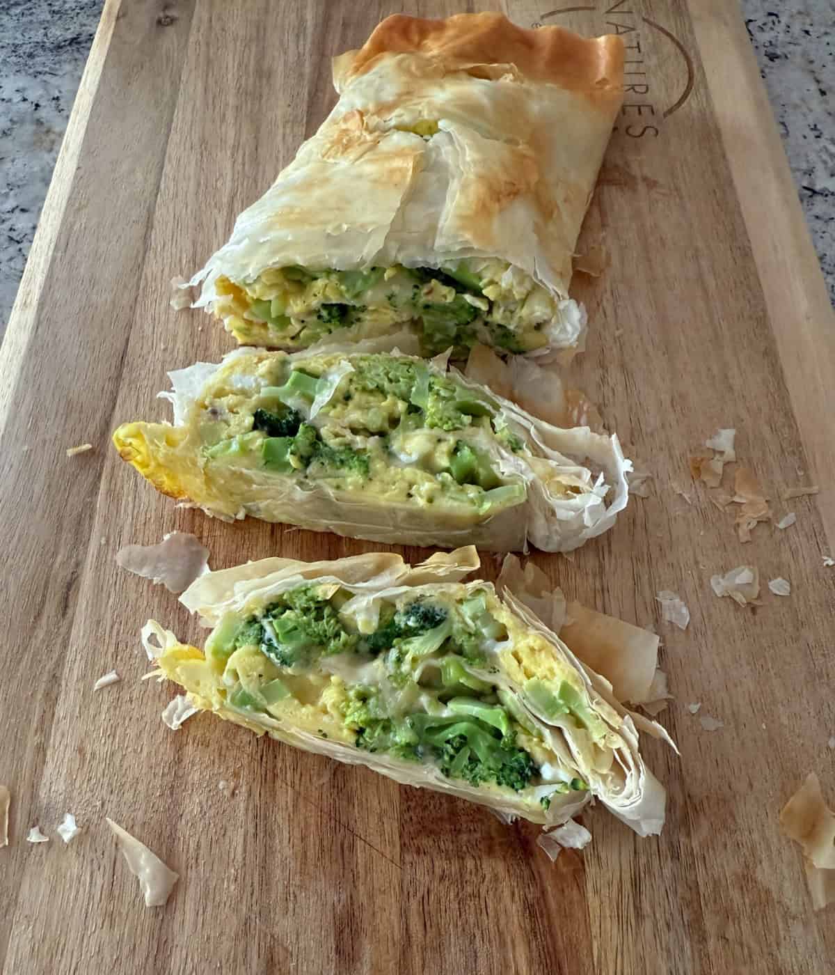 Egg and Broccoli Strudel cut into slices on a wood cutting board.