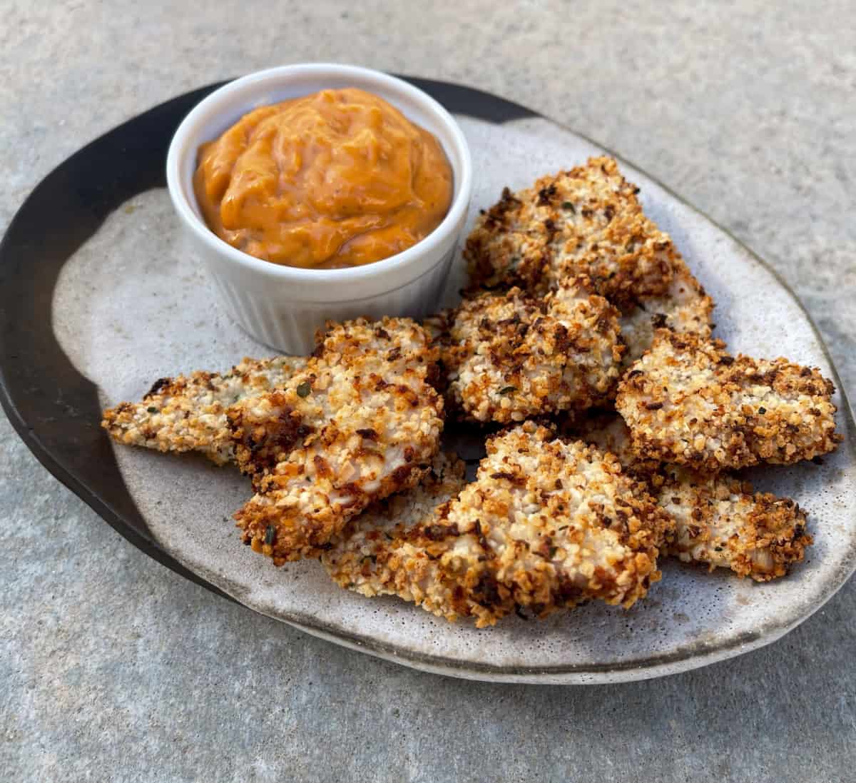 Air fryer ranch chicken nuggets on small ceramic plate with ramekin of special sauce for dipping.
