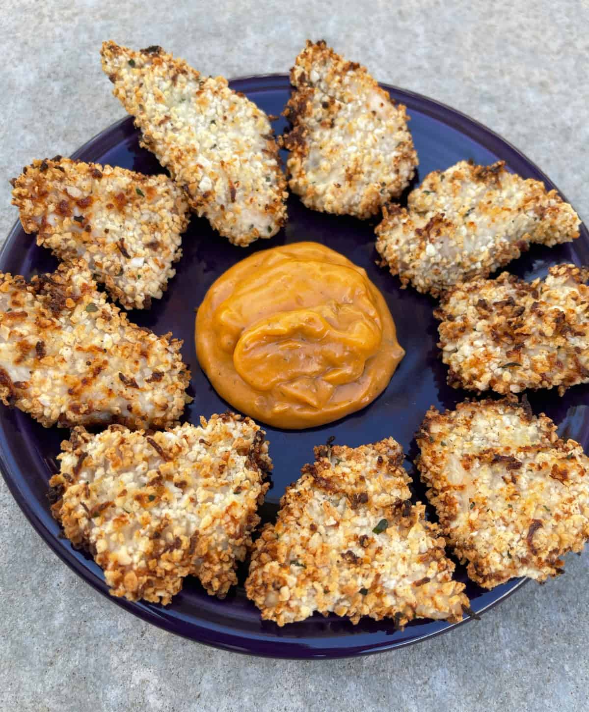 Air fryer ranch chicken nuggets on purple plate with special sauce for dipping.