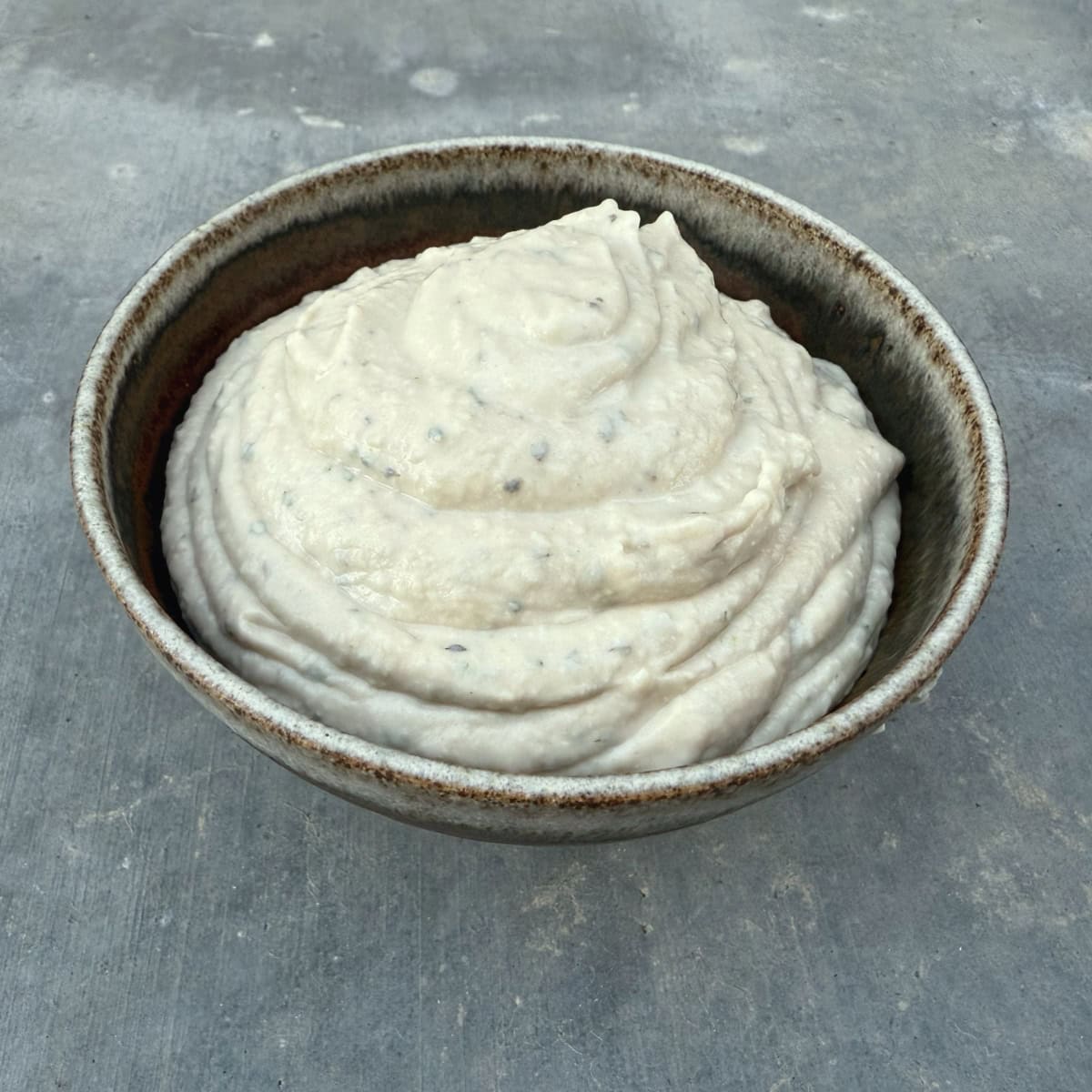 Creamy Tuscan White Bean Dip in small brown ceramic bowl.