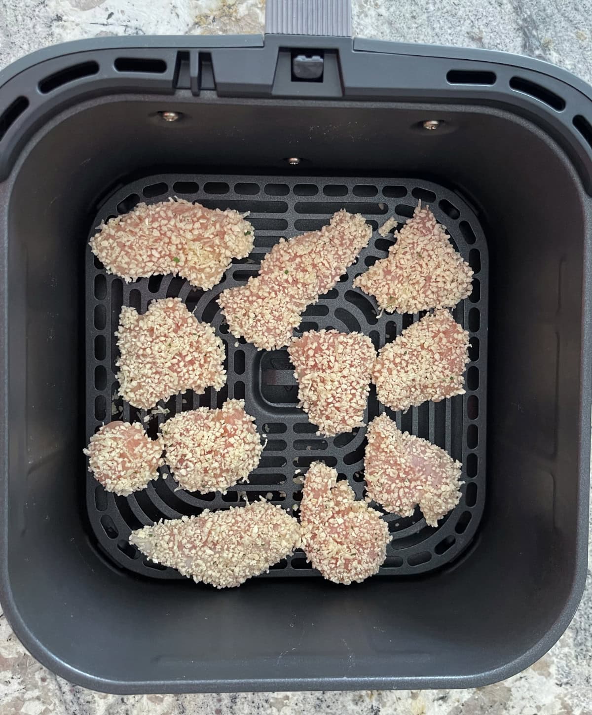 Uncooked ranch chicken nuggets in air fryer basket.