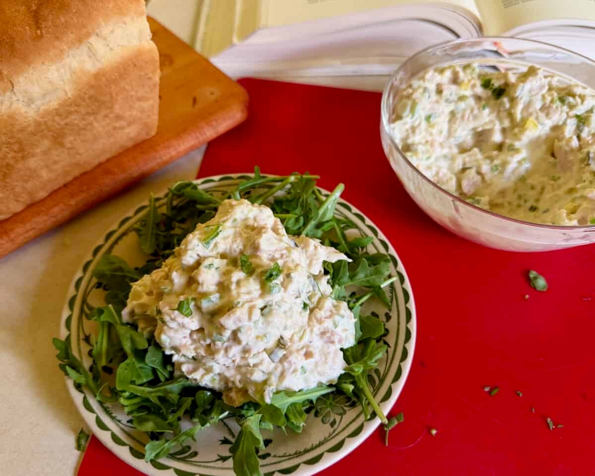 tuna salad on bed of arugula with loaf of homemade sandwich bread in background