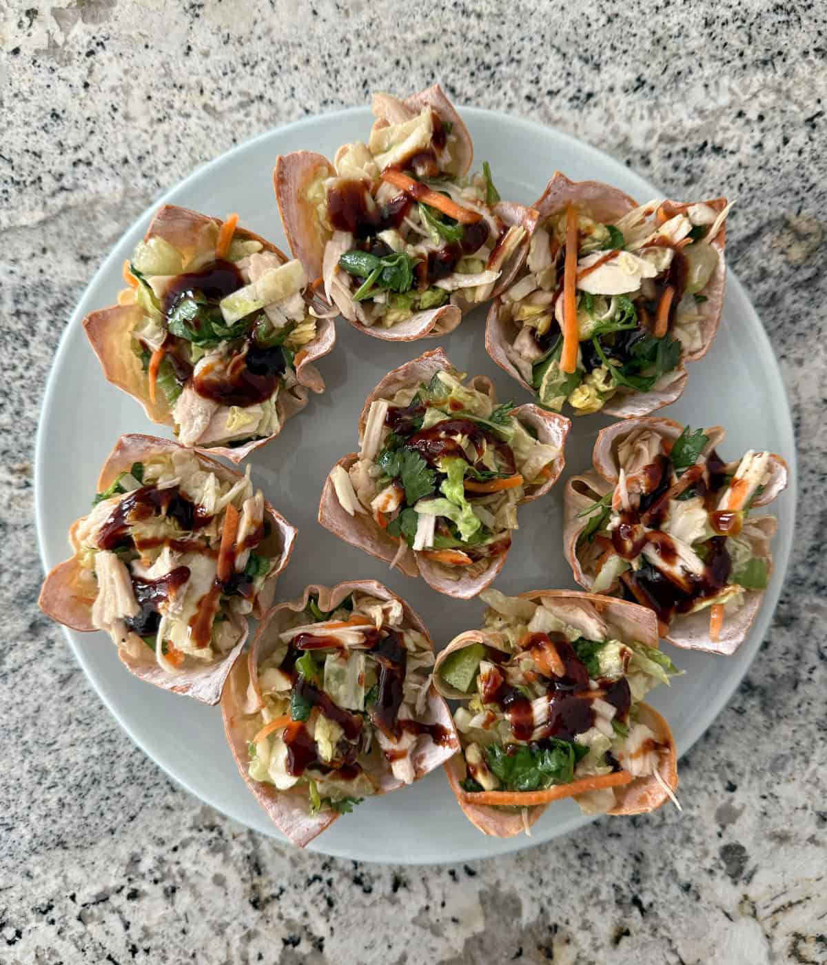 Asian chicken salad wonton cups on round blue plate.