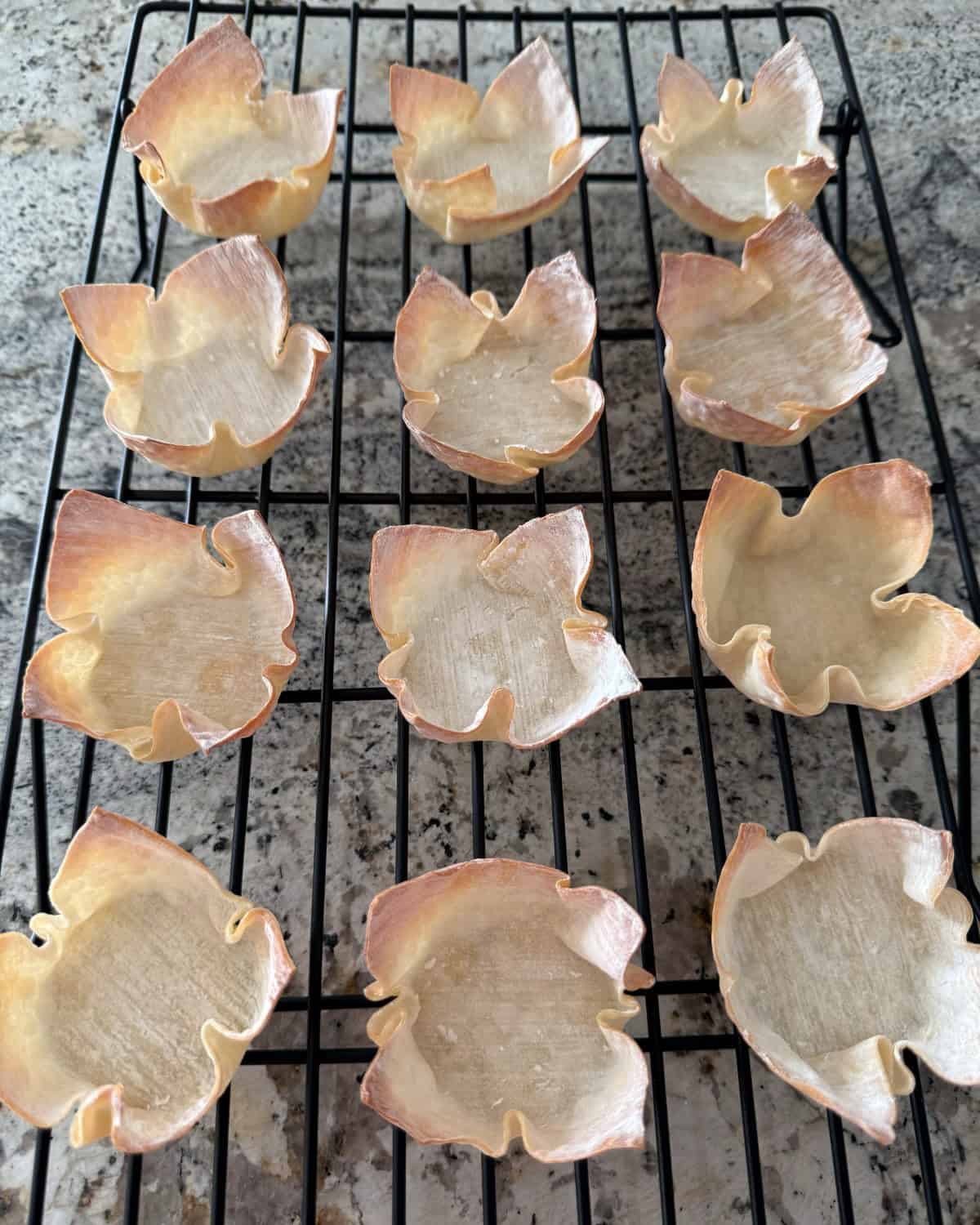 Fresh baked wonton cups cooling on wire rack.