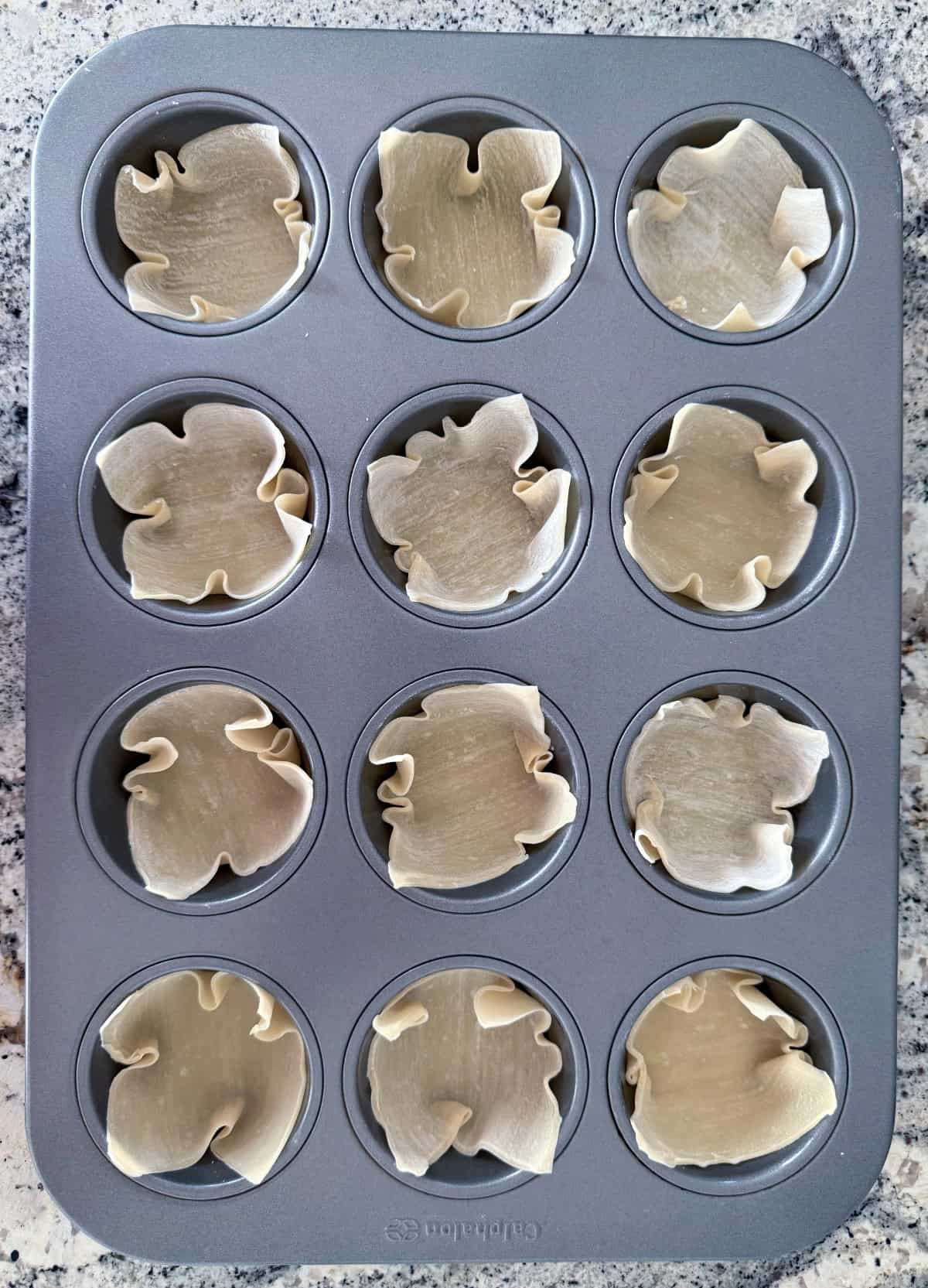 Wonton wrappers pressed into standard muffin pan.