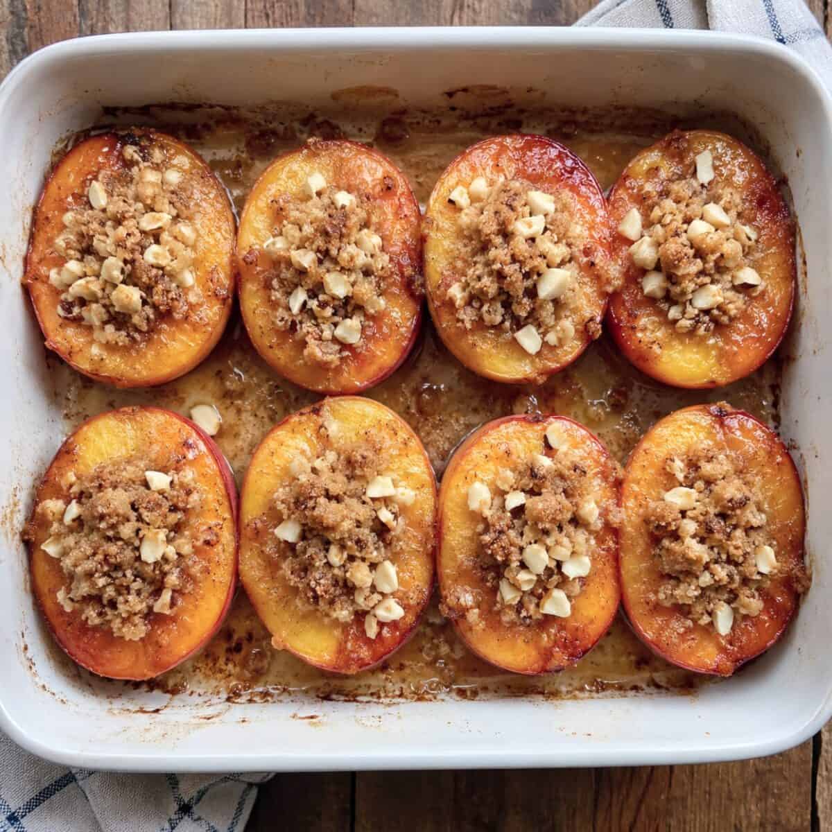 Streusel-topped oven-roasted peaches in a baking dish.